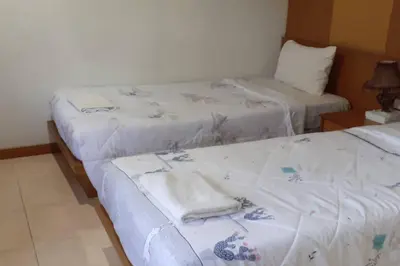 two beds in a hotel room with towels on them at Praew Mansion in Kamala Beach