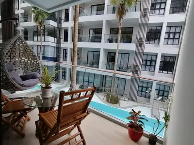 a balcony with a hammock and a large building at Palmyrah Surin Beach By Risa in Surin Beach