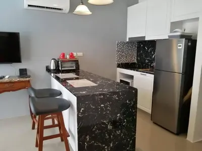 a kitchen with a black counter top and a refrigerator at Palmyrah Surin Beach By Risa in Surin Beach