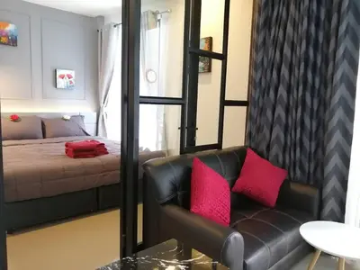 a bedroom with a couch and a bed with red pillows at Palmyrah Surin Beach By Risa in Surin Beach