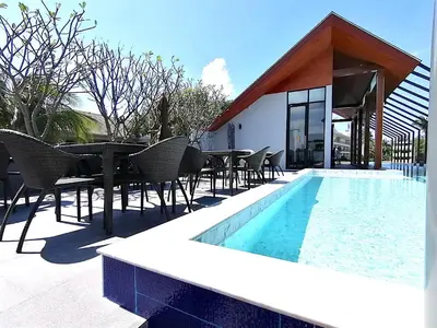 a patio with a table and chairs next to a pool at Palmyrah Surin Beach By Risa in Surin Beach
