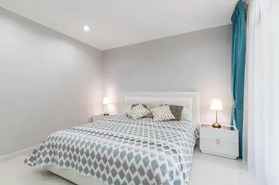 a white bedroom with a bed and two lamps at The Kamala Regent by My Home Phuket in Kamala Beach