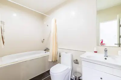 a white bathroom with a tub and a toilet and a sink at The Kamala Regent by My Home Phuket in Kamala Beach