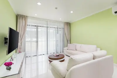 a living room with white furniture and a large window at The Kamala Regent by My Home Phuket in Kamala Beach