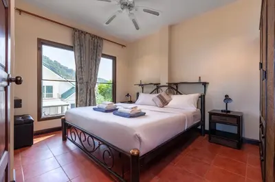 a bedroom with a bed and a large window at Sabai Villa Kata by RESAVA in Kata Beach