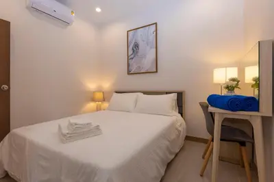 a small bedroom with a white bed and a desk at Palmetto by Holy Cow, 2-BR, jungle view in Karon Beach