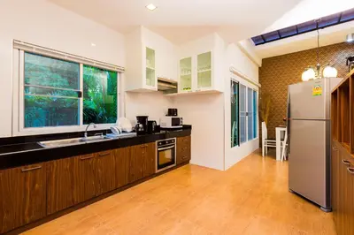 a kitchen with wooden cabinets and a stainless steel refrigerator at Irawan House in Ao Nang Beach