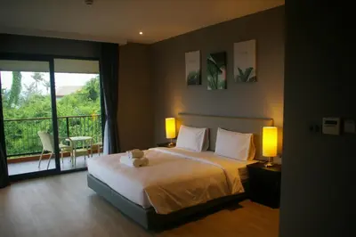a bedroom with a bed with two lamps and a balcony at Aonang Inn in Krabi town