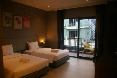 a hotel room with two beds and a balcony at Aonang Inn in Krabi town