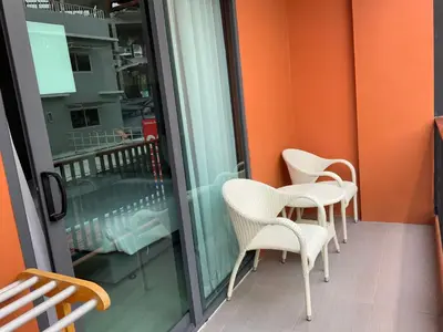 a balcony with chairs and a glass door at Aonang Inn in Krabi town
