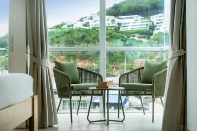 a room with two chairs and a table in front of a window at Ozone Kata -Great location, rooftop pool, convenient studio in Karon Beach