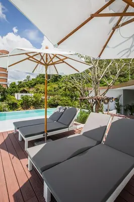a patio with chairs and an umbrella and a pool at Palmetto Condominium in Karon Beach