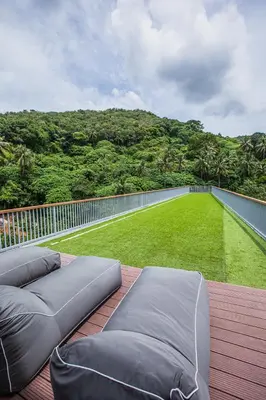 a balcony with a couch and a green lawn at Palmetto Condominium in Karon Beach