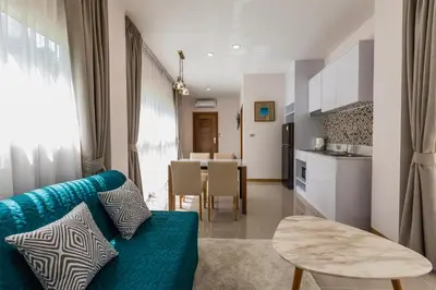 a living room with a blue couch and a kitchen at Palmetto Condominium in Karon Beach
