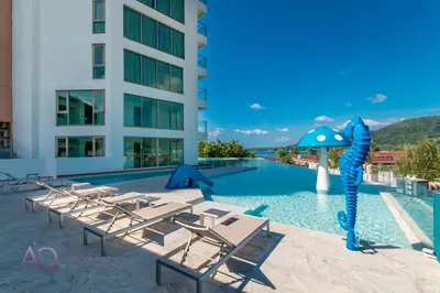 a swimming pool with lounge chairs and an infront of a building at Luxury Lagoon 1bedroom Apartment in Kamala Beach