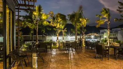 a patio with tables and chairs and palm trees at night at Relife Windy by Nataly in Phuket Town