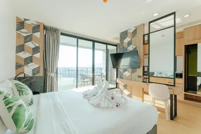 a hotel room with a bed and a desk with a television at Sky Wave Patong in Patong Beach