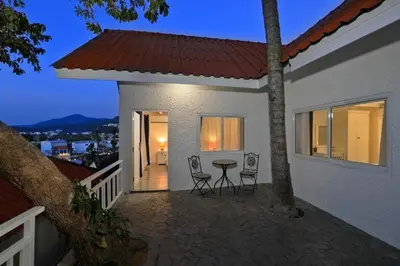 a house with a table and chairs on a balcony at Kata White Villas in Kata Beach
