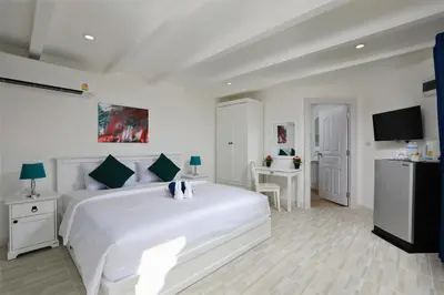 a white bedroom with a large white bed and a desk at Kata White Villas in Kata Beach