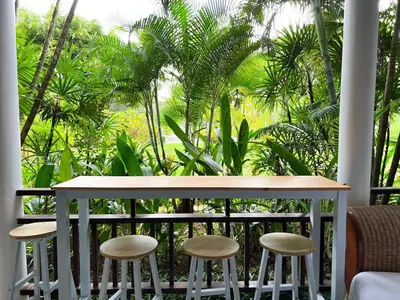 a table and stools on a balcony with palm trees at The Sands 3 Bedrooms Beachside Apartment in Naiharn in Nai Harn Beach