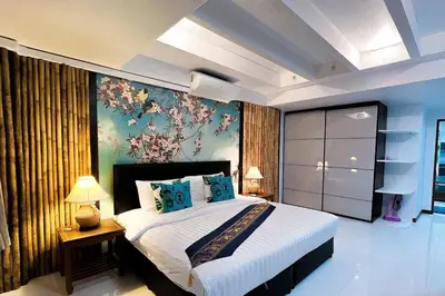 a bedroom with a large bed with a painting on the wall at The Sands 3 Bedrooms Beachside Apartment in Naiharn in Nai Harn Beach