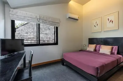 a bedroom with a bed and a tv and a window at Beautiful 3 bedroom pool villa with 65inch smart tv Located near popular Bangtao beach and laguna Phuket in Bang Tao Beach