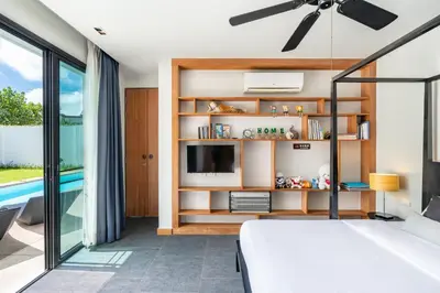 a bedroom with a bed and a tv and a pool at Beautiful 3 bedroom pool villa with 65inch smart tv Located near popular Bangtao beach and laguna Phuket in Bang Tao Beach