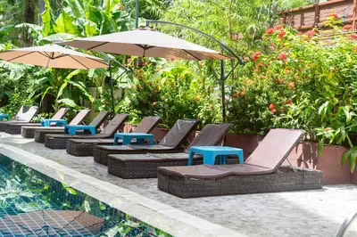 a row of lounge chairs and umbrellas next to a pool at Patong Central Residence and Apartment in Patong Beach