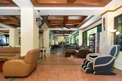 a living room with couches and chairs in a library at Patong Central Residence and Apartment in Patong Beach