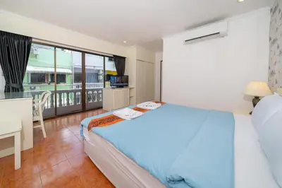 a bedroom with a bed and a desk and a balcony at Patong Central Residence and Apartment in Patong Beach