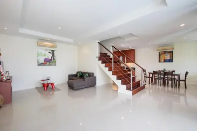 a living room with a staircase and a dining room at Prima Villas Karon Phuket in Karon Beach