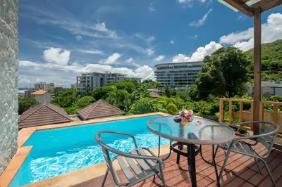 a patio with a table and chairs next to a swimming pool at Prima Villas Karon Phuket in Karon Beach