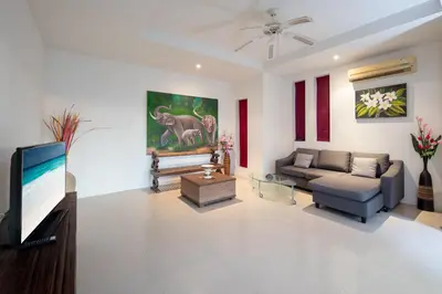 a living room with a couch and a tv at Prima Villas Karon Phuket in Karon Beach