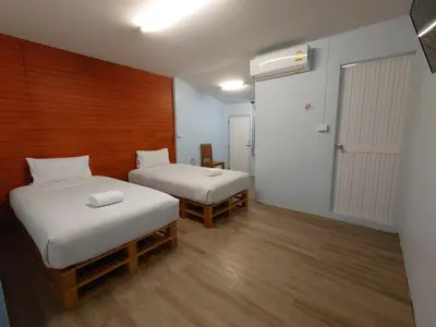 a small room with two beds and a door at Baan Kim Lian SHA in Phuket Town