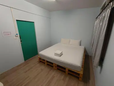 a small bed in a room with a green door at Baan Kim Lian SHA in Phuket Town