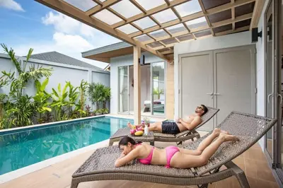 two women laying on chairs next to a swimming pool at Beach escape at Villa Dalaa 8 in Kamala Beach
