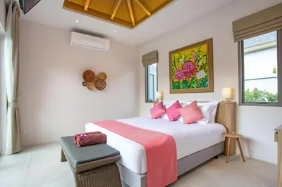 a bedroom with a large white bed with pink pillows at Beach escape at Villa Dalaa 8 in Kamala Beach