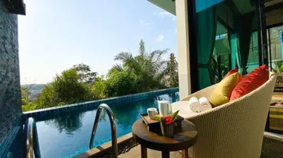 a balcony with a chair and a table and a pool at Silla Villa Private Pool & Sea View in Kata Beach