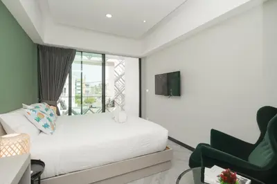 a bedroom with a white bed and a green chair at Yanud Residence in Phuket Town