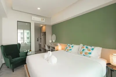 a bedroom with a large white bed and a green chair at Yanud Residence in Phuket Town