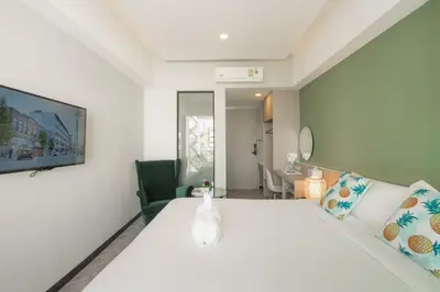 a bedroom with a white bed and a green chair at Yanud Residence in Phuket Town
