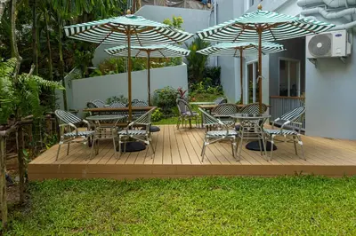 a wooden deck with tables and chairs with umbrellas at Palmetto by Holy Cow, 2-BR, Sea View in Karon Beach