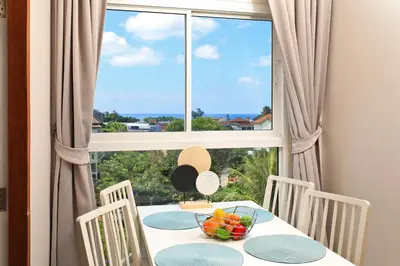 a table with a bowl of fruit in front of a window at Palmetto by Holy Cow, 2-BR, Sea View in Karon Beach