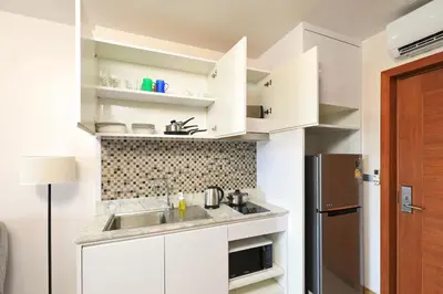 a kitchen with white cabinets and a sink and a refrigerator at Palmetto by Holy Cow, 2-BR, Sea View in Karon Beach