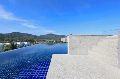 a swimming pool with blue tiles on the side of a house at Relife Windy by Holy Cow, studio with sofa-bed in Rawai Beach