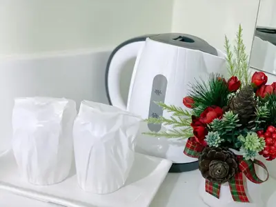 a white plate with a bouquet of flowers and a tea kettle at Nai Yang Residence in Nai Yang Beach