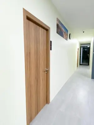 a hallway with a wooden door and white walls at Nai Yang Residence in Nai Yang Beach