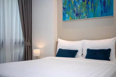 a white bed with blue pillows in a bedroom at 1bdr Pool Access Apartment Bangtao #5103 in Bang Tao Beach