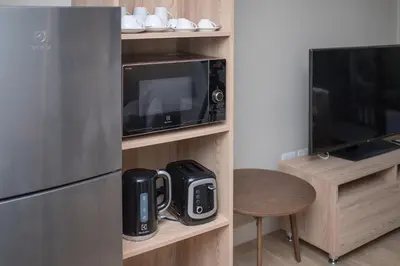 a kitchen with a microwave and a tv and a table at 1bdr Pool Access Apartment Bangtao #5103 in Bang Tao Beach