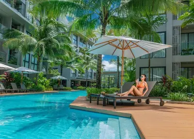 a woman sitting in a chair next to a swimming pool at 1bdr Pool Access Apartment Bangtao #5104 in Bang Tao Beach